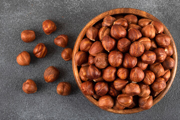 Top view of a bowl full of hazelnuts on dark background