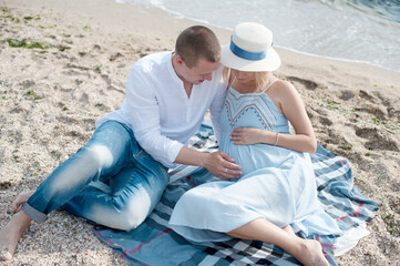 Happy future parents couple have a rest sitting near sea