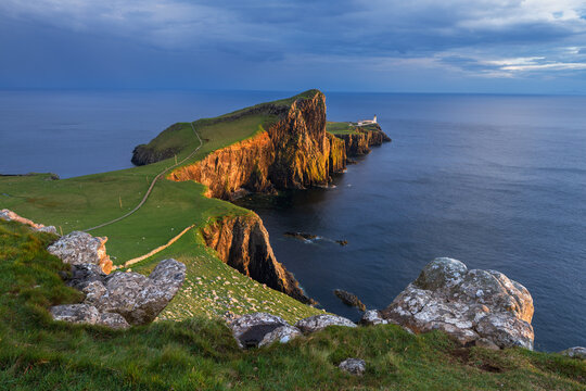 Golden evening sunlight casting on cliffs of Neist Point Lighthouse on the Isle of Skye, Scotland, UK.