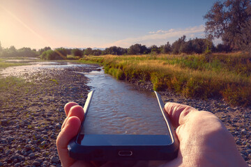 The river flows into the phone. Drying river Karatal. Kazakhstan, Zhetysu region. Summer.
