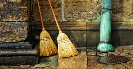 Closeup shot of two brooms leaning on the wall