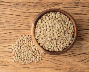 Raw lentils in a bowl over wooden table