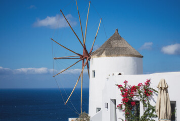 Old traditional whitewashed greek windmill on Santorini island in Oia town with stairs in street. Greece