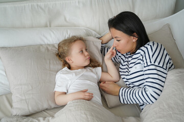 Mother lying in comfortable bed with foster daughter after sleeping. Healthy sleep in children