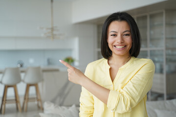Smiling female homeowner pointing aside, recommending service, real estate sale offer at new home