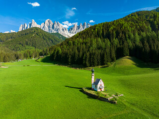 Aerial view of the Odle and iconic chapel of St. John in Ranui in spring, St. Magdalena, Funes Valley, Dolomites, South Tyrol, Italy