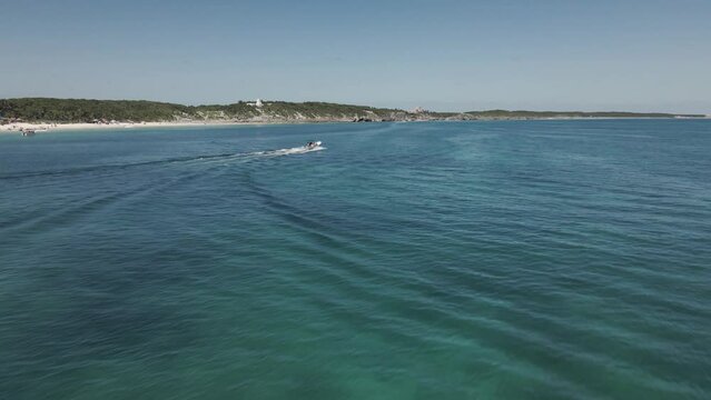 Drone shot of a boat speeding through the ocean on a sunny summer day