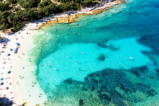 Tourists swimming in the turquoise transparent sea at Emplisi beach, overhead view, Fiskardo, Kefalonia, Ionian Islands, Greek Islands, Greece