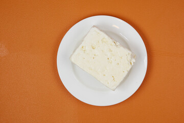 feta cheese on a plate on orange background 