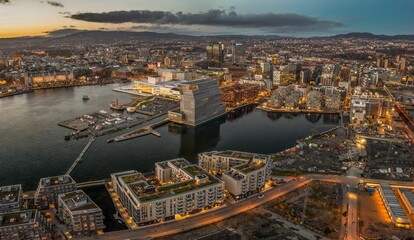 Aerial shot of Oslo at sunset, with lots of buildings and lights, surrounded by sea, Norway - obrazy, fototapety, plakaty