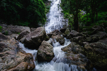 Fototapeta premium Stream waterfall on rocks in the forest. Waterfall stream on rocks. Beautiful waterfall stream. Waterfall stream in forest Thailand