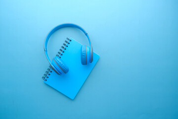 Audio book concept. Headphones and notepad on blue background 
