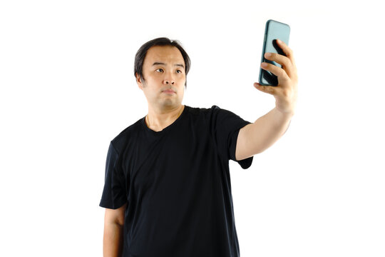 Asian man wear black t-shirts. Using mobile To take a picture  or selfie of himself isolated on white background.