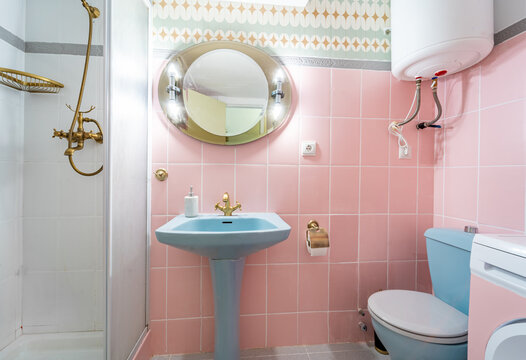 Retro and colorful bathroom.  Mid Century pink and blue tiles interior with vintage mirror.