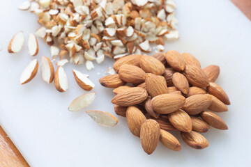 Dry almond and almond slice on white cut board.