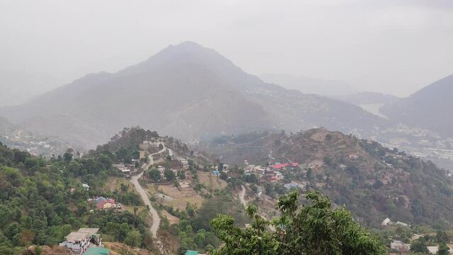 Aerial shot of houses on the Uttarakhand Mountains range, trees and foggy mountains in India