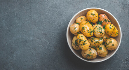 Boiled unpeeled potatoes with dill and butter on a dark background. Side view, horizontal