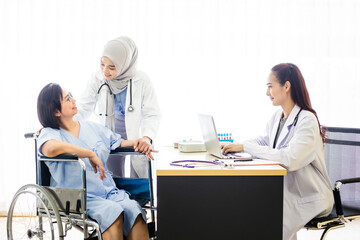 Senior patient woman sitting on wheelchair and having consultation with Muslim and Asian doctor in hospital. Healthcare and assistance concept.