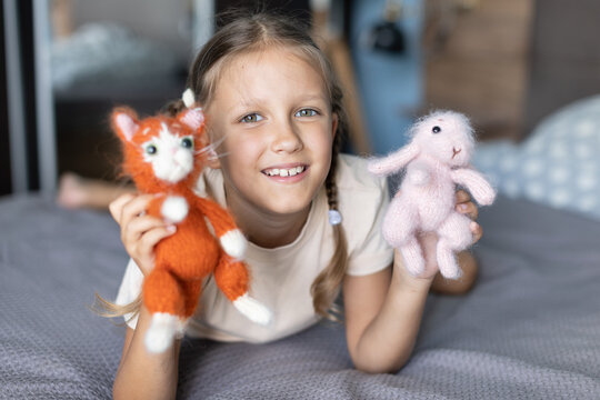a girl of eight years old plays with knitted toys