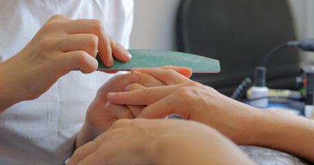 Obraz na płótnie Canvas Manicurist files the shape of the nails with a special nail file, close up view