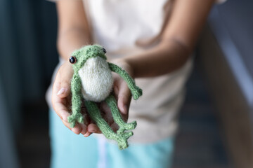 green knitted frog in the hands