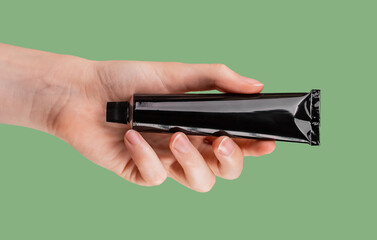 Hand with cream tube mockup. Organic, eco beauty product from natural ingredients. Skin care, makeup concept on green background. High quality photo