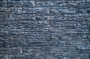 Black tiles imitating stone on wall close