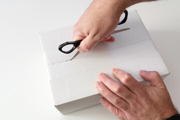 close-up of person opening parcel using scissors
