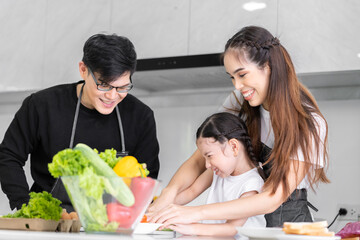 Asian girl learning to cook with mom and dad. Do activities together with your family in a fun and joyful way. There is a father and mother taking care of them closely.