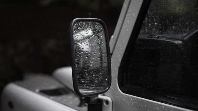 Raining over SUV side view mirror in a cloudy day