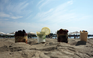 Fototapeta na wymiar cold drinks cocktail with fruits on a beach with summer hat