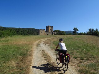 Obraz premium jeune femme à Vélo montant vers un château médiéval d'Arques dans l'Aude sud de France