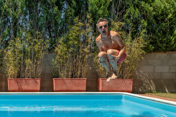 Middle-aged white man dives into the pool with swimming goggles, cannonball style