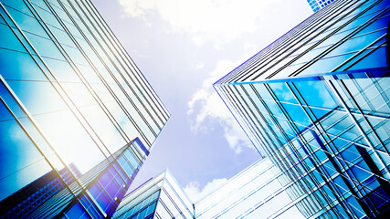 Fototapeta na wymiar Glass buildings business concept. The glass facade of a skyscraper with a mirror reflection of sky windows. Modern office building with glass facade on a clear sky background. 3d Rendering