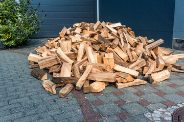 Stock of firewood for heating house. Stacked dried logs in front of the house