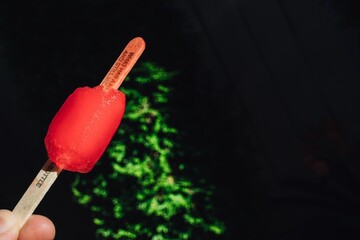 hand holding red half eaten popsicle