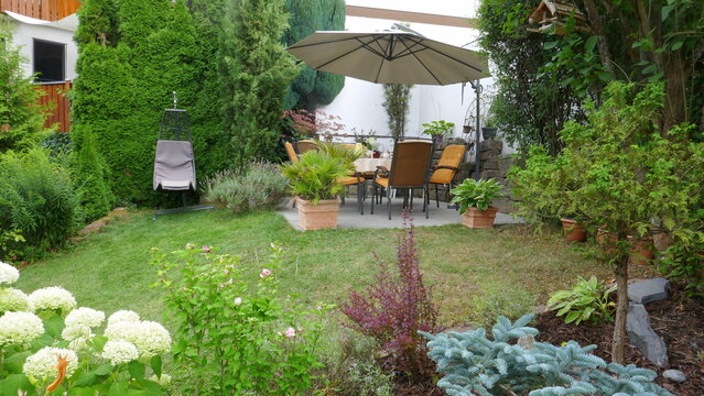 gem&uuml;tliche Gartenterrasse inmitten von diversen Pflanzen und Blumen