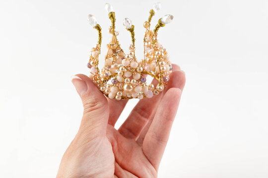 Blurred image of a child's golden crown in a girl's hand on a light background.