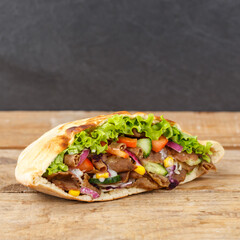 Döner Kebab Doner Kebap fast food in flatbread on a wooden board square with copyspace copy space - obrazy, fototapety, plakaty