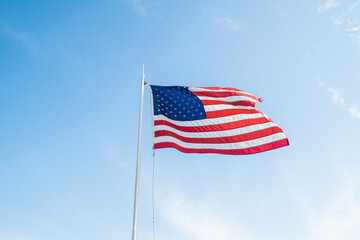 America flag waving in the wind over a bright blue and sunny sky background
