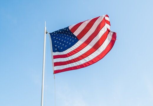 America flag waving in the wind over a bright blue and sunny sky background