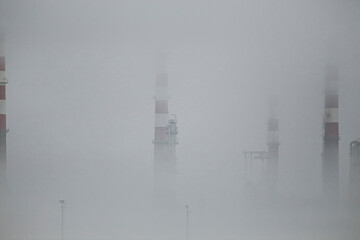Oil refinery chimeys in the smog