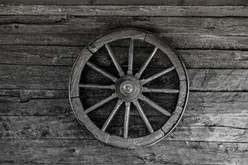 Old wooden wheel on a wooden wall.