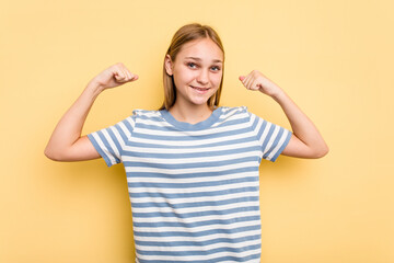 Young caucasian girl isolated on yellow background showing strength gesture with arms, symbol of feminine power