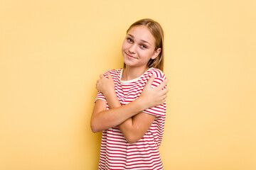 Young caucasian girl isolated on yellow background hugs, smiling carefree and happy.