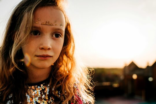 portrait of a girl in a sequin dress and face paints at sunset
