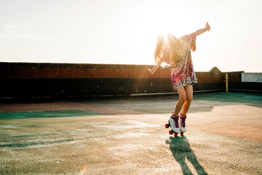 girl dancing in a sequin dress and roller boots at sunset
