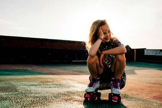 portrait of a young girl in a sequin dress roller booting at sunset