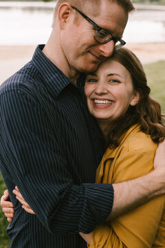 Adult married couple hugs and smiles on lakeshore