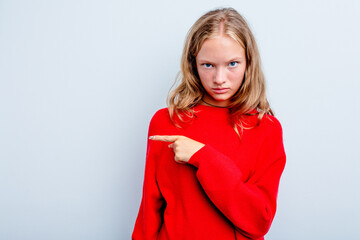 Caucasian teen girl isolated on blue background smiling and pointing aside, showing something at blank space.